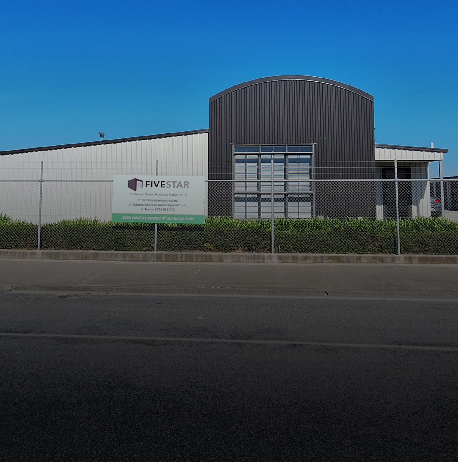 Photo outside the front of Five Star Self Storage Facility with their sign on the fence on a clear blue sky day | Links to the 'Who We Are' page
