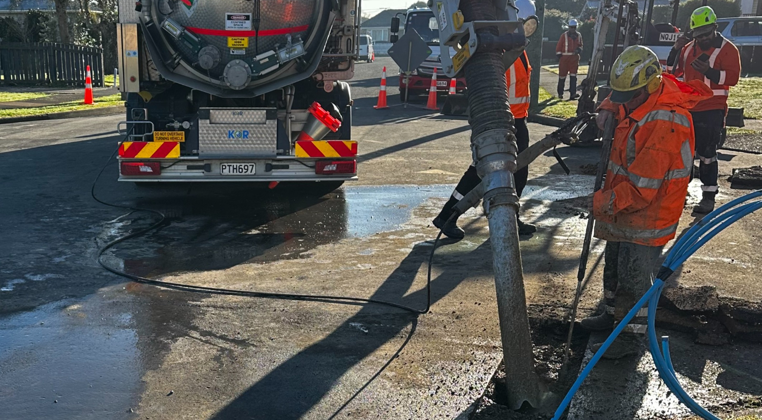Two workers working on hydro excavation services in a suburban street