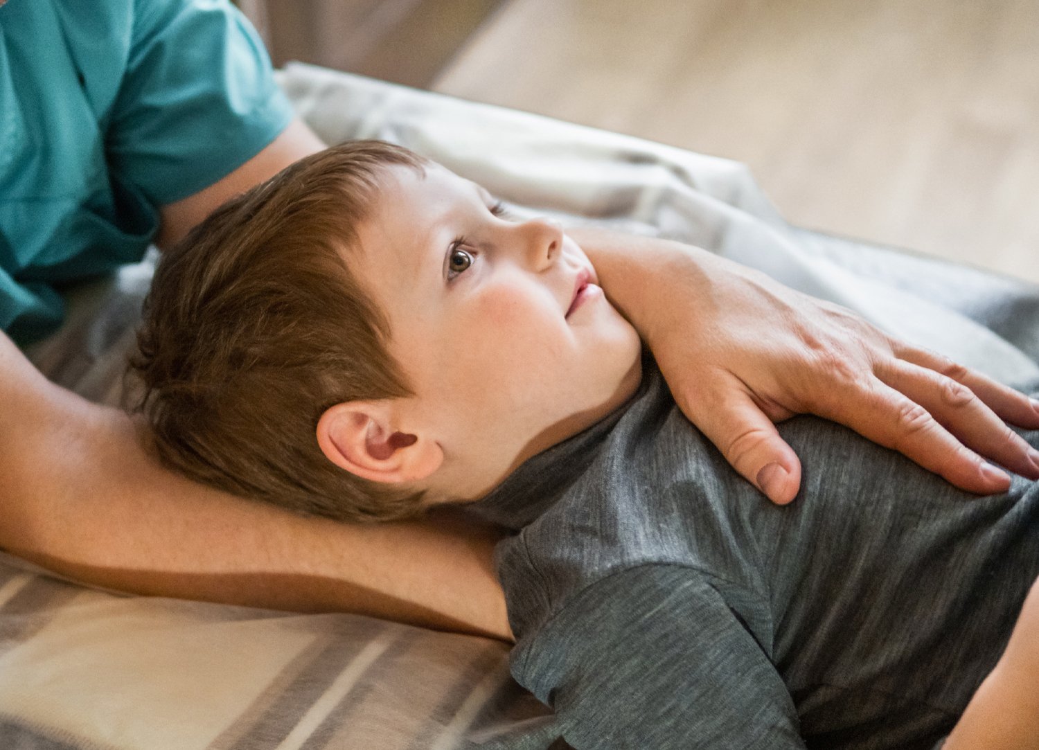 Image of a female patient's head laying on a table with an osteopath's hands under her cranium - links to 'Cranial Osteopathy' page