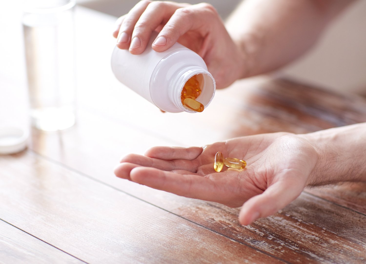 Close up view of someone tipping medicine capsules into their hand - links to 'Metagenics' page