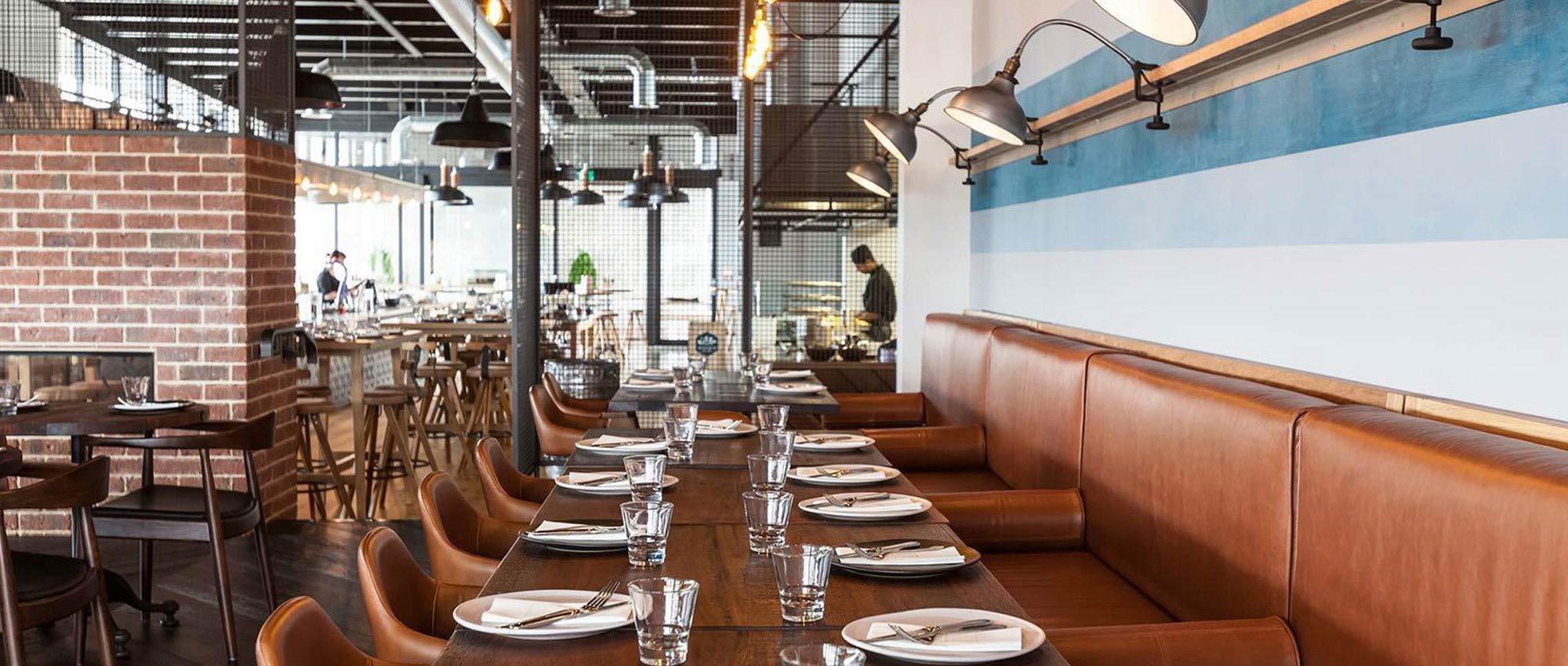 Custom commercial fit out for a restaurant sitting area with custom upholstered booth chairs, tables, and freestanding chairs