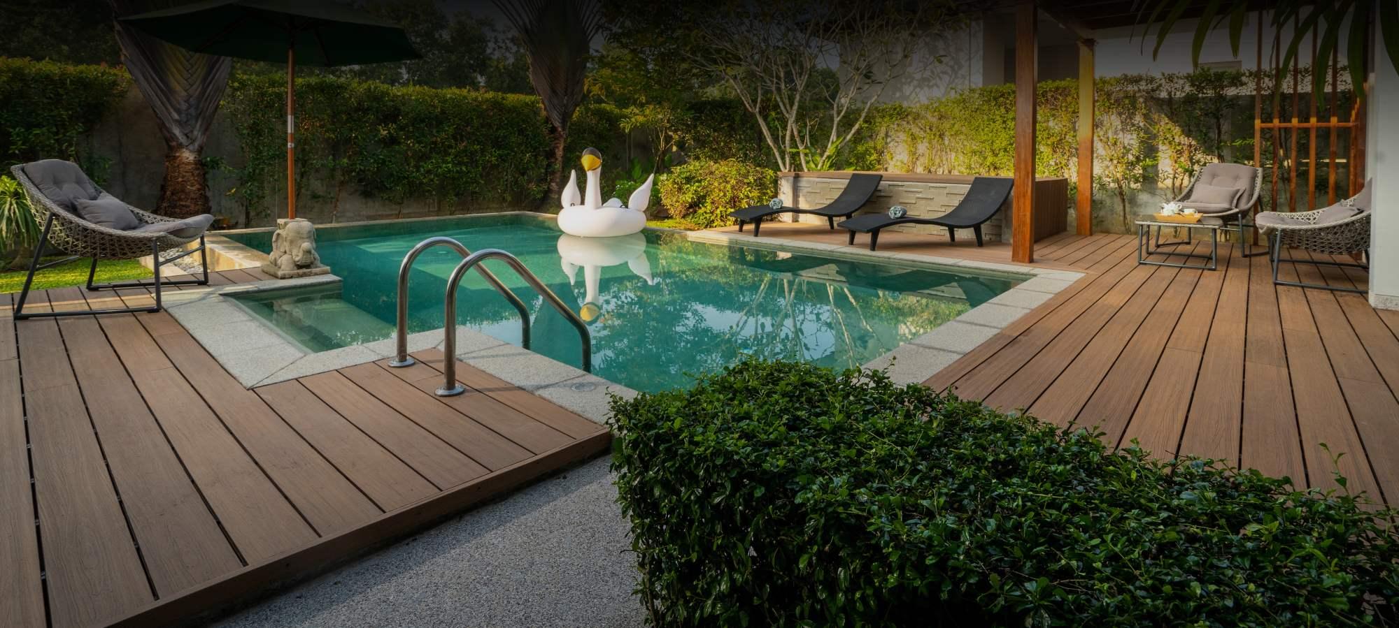 Beautifully designed backyard with a big wood deck, vine-covered fences, and a clear blue pool with a blow up swan in it