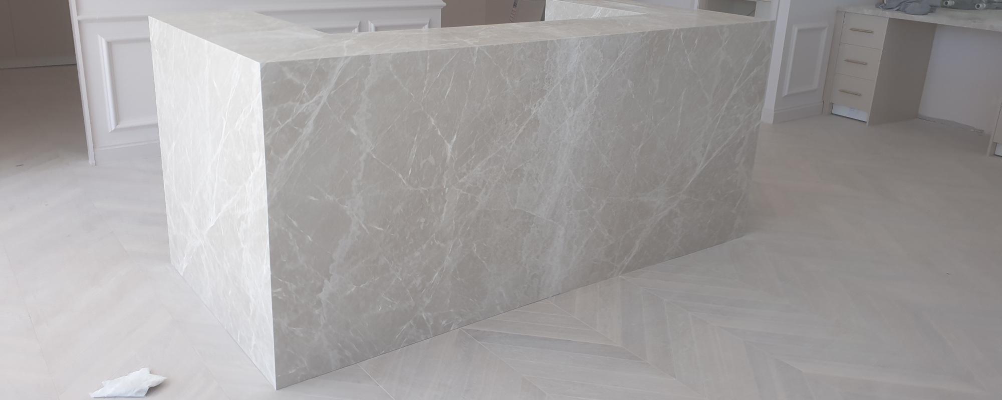 Thick white marble reception desk for a commercial space with white wood floors and white painted classic styled walls