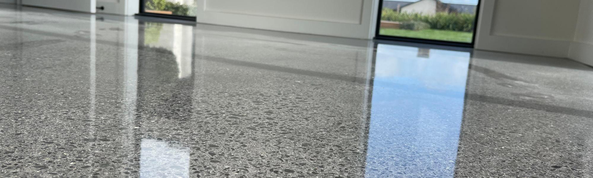 Extremely reflective polished concrete floor in a residential home with a nice garden showing through the windows