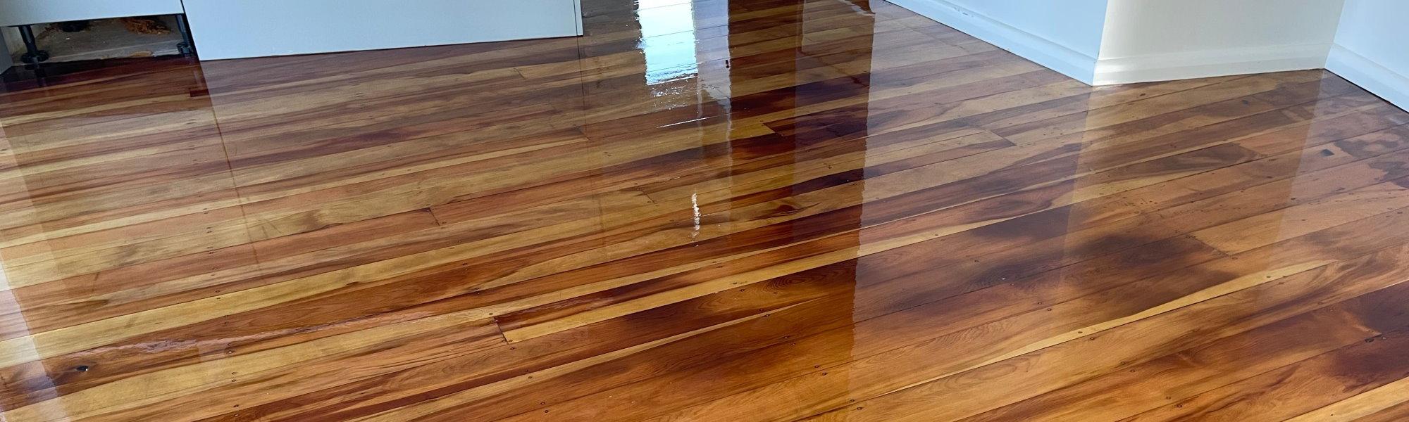 Shiny refinished timber flooring in a residential home with white walls and old oak plank floors