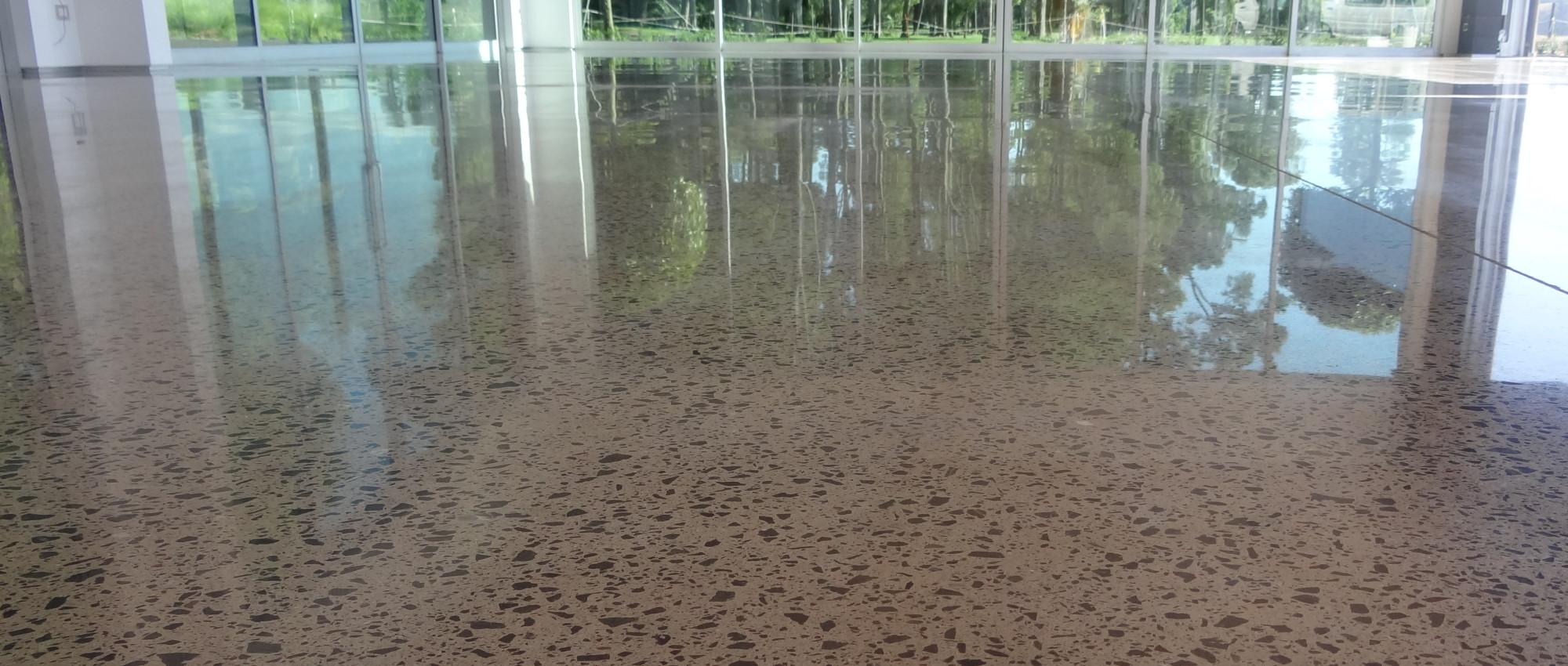 Spacious polished concrete floor in a commercial building with large windows letting the sun in on to the shiny reflective concrete