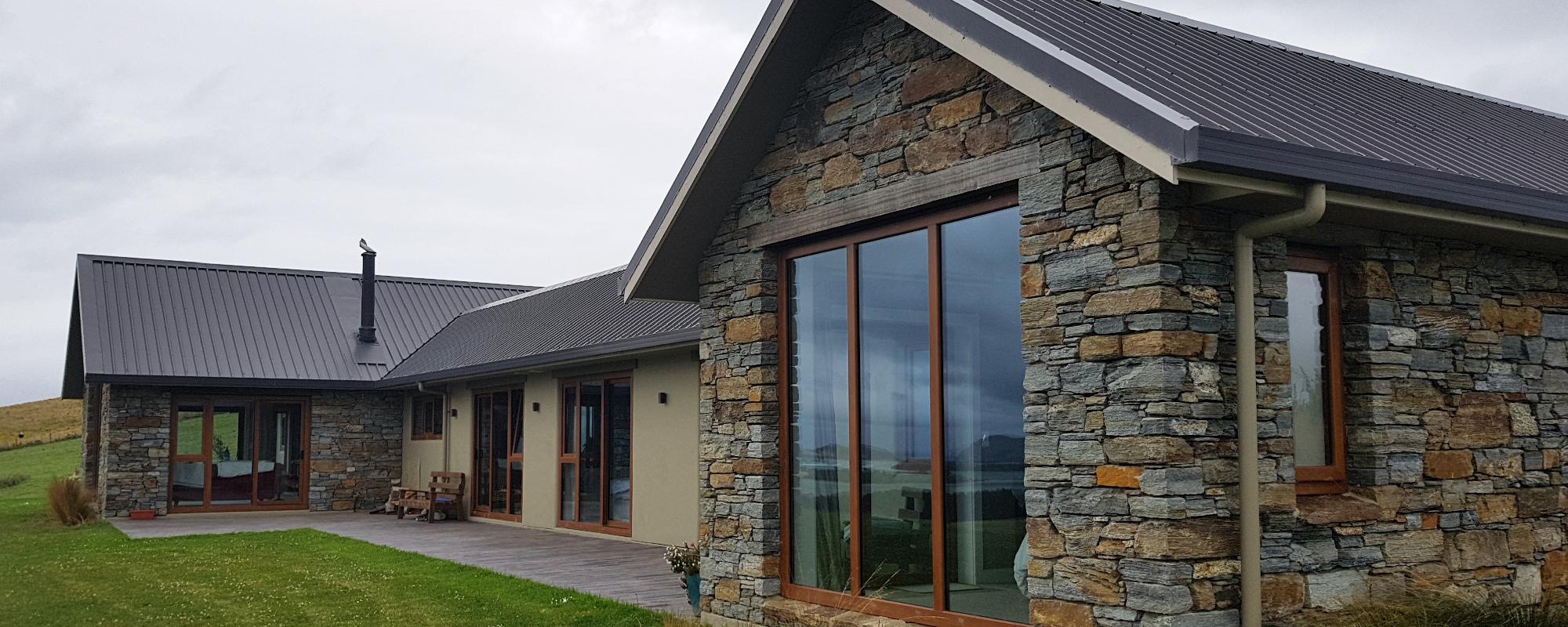 Large rural house partly covered in stone bricks with brown uPVC window and door frames