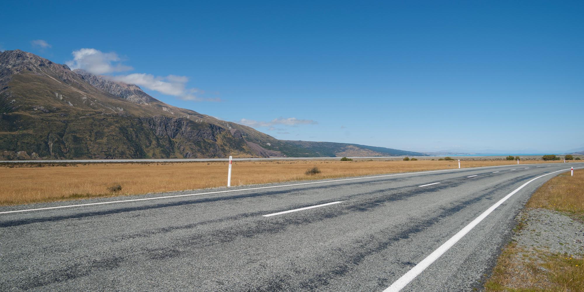 Highway in the countryside with dead fields and large hills and a lake in the background