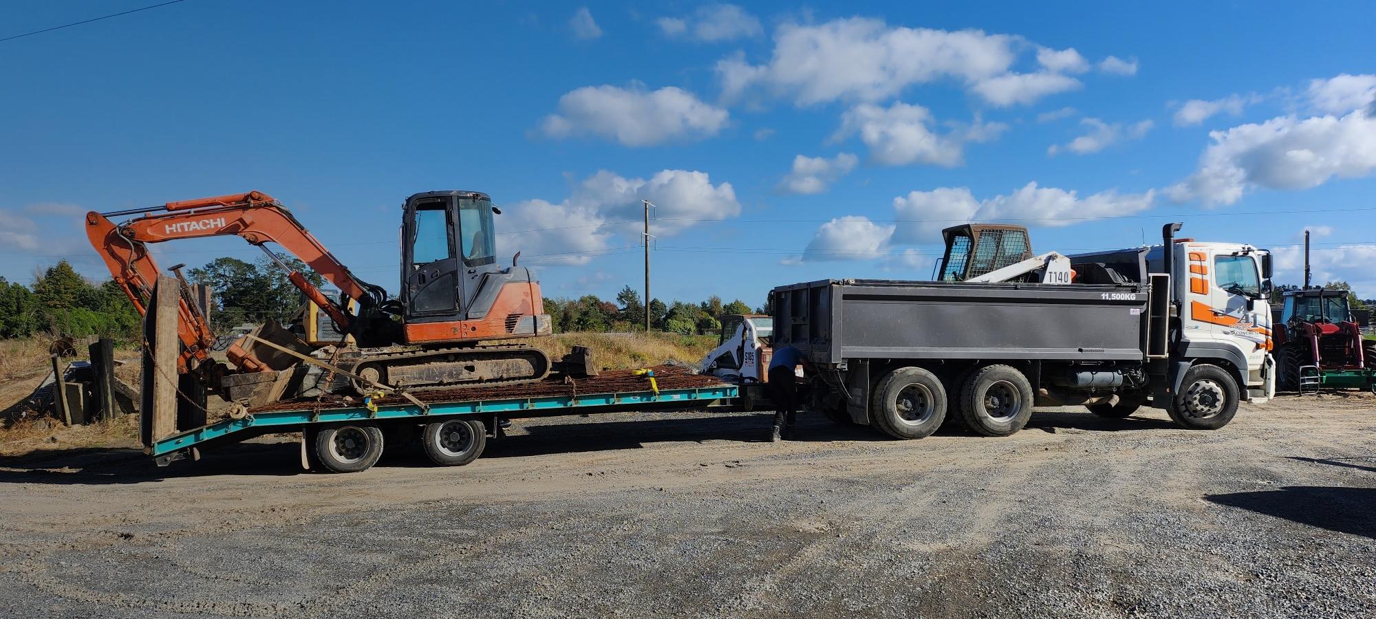 Large White and orange A1 Bobcats & Concrete truck with one carriage and a trailer with an orange digger on the back for transport