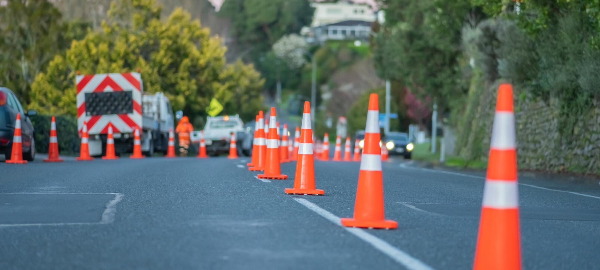 Roadworks vehicles parked up on the street with cones lining the street right down the middle letting cars past