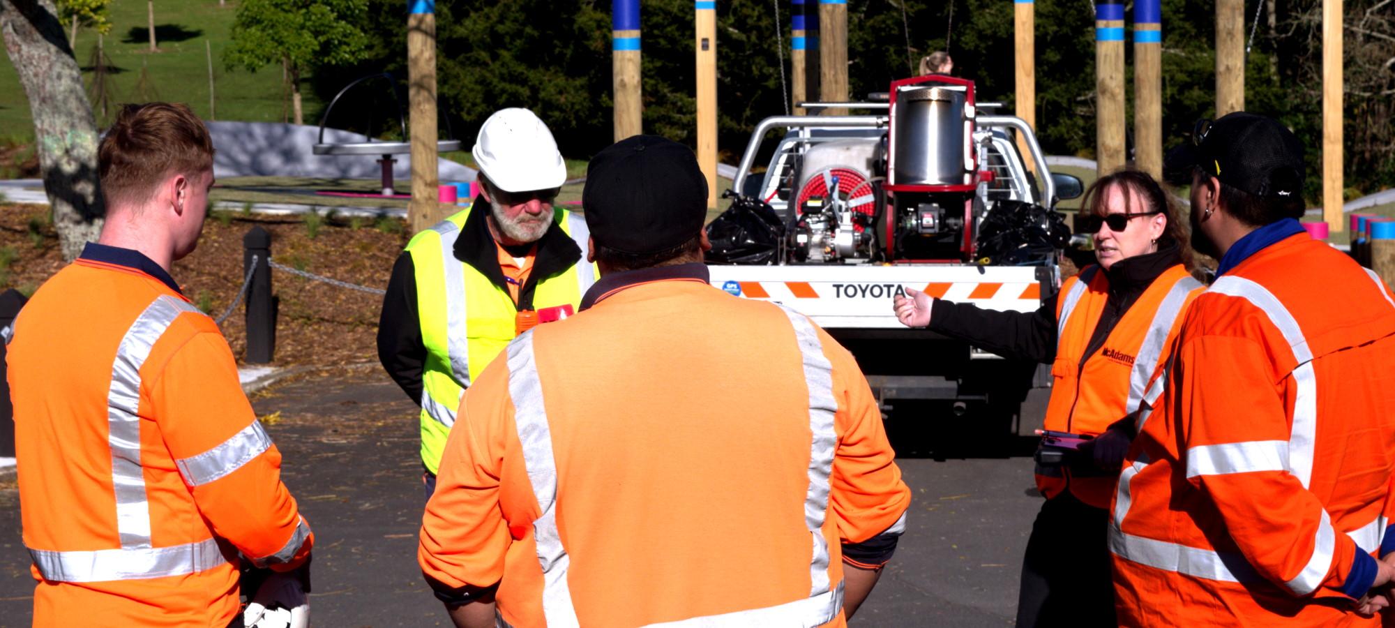 Traffic Management Waikato team members parked up at the local park, assessing a situation as they stand in a circle