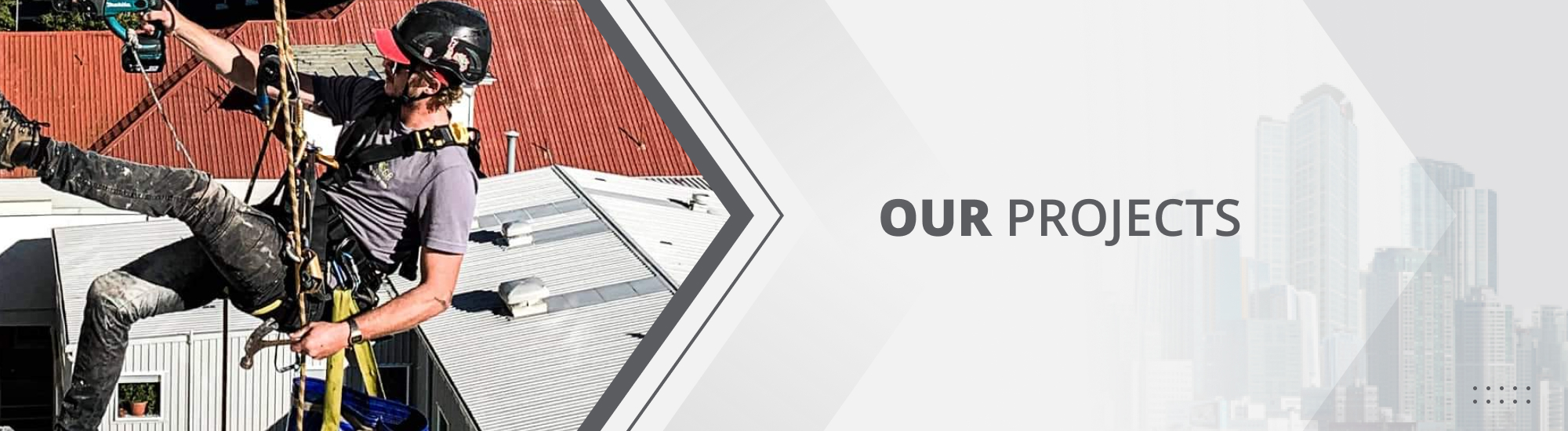 Abseiler on the side of a Waikato building, in a black helmet and safety gear while using a power tool on the building facade