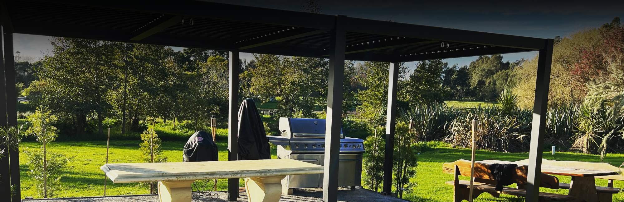 Outdoor canopied barbeque area with heaps of room for dining outside with the vibrant green lawn and surrounding trees