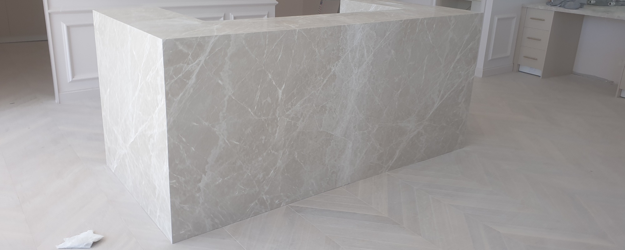 Thick white marble reception desk for a commercial space with white wood floors and white painted classic styled walls