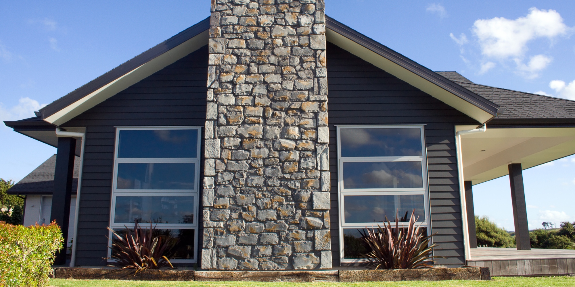 Beautiful new Hamilton home with a large stone fireplace, black painted weatherboard, and contrasting white accents.