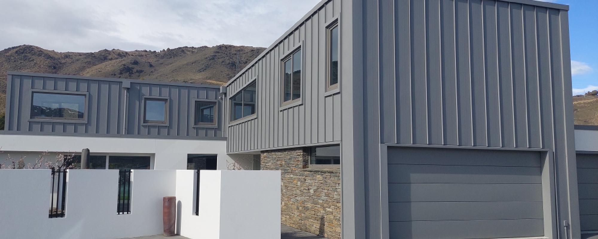 Modern box-like predominantly grey home with matching uPVC window and garage door framing 
