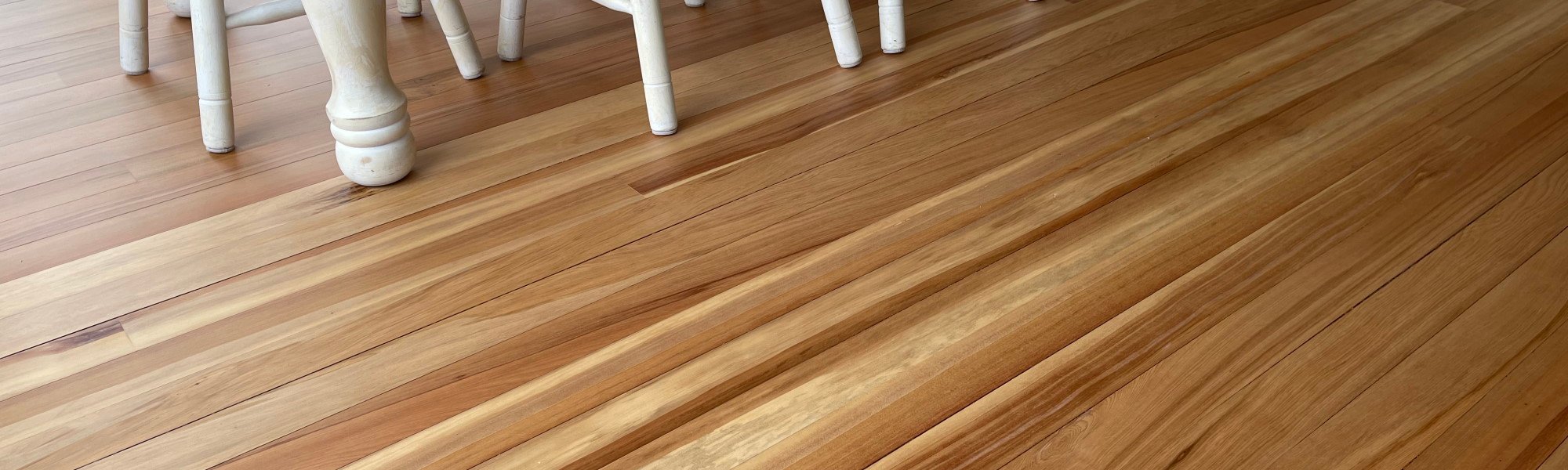 Smoothly sanded and finished timber floor in a residential dining room with a white dining table set 
