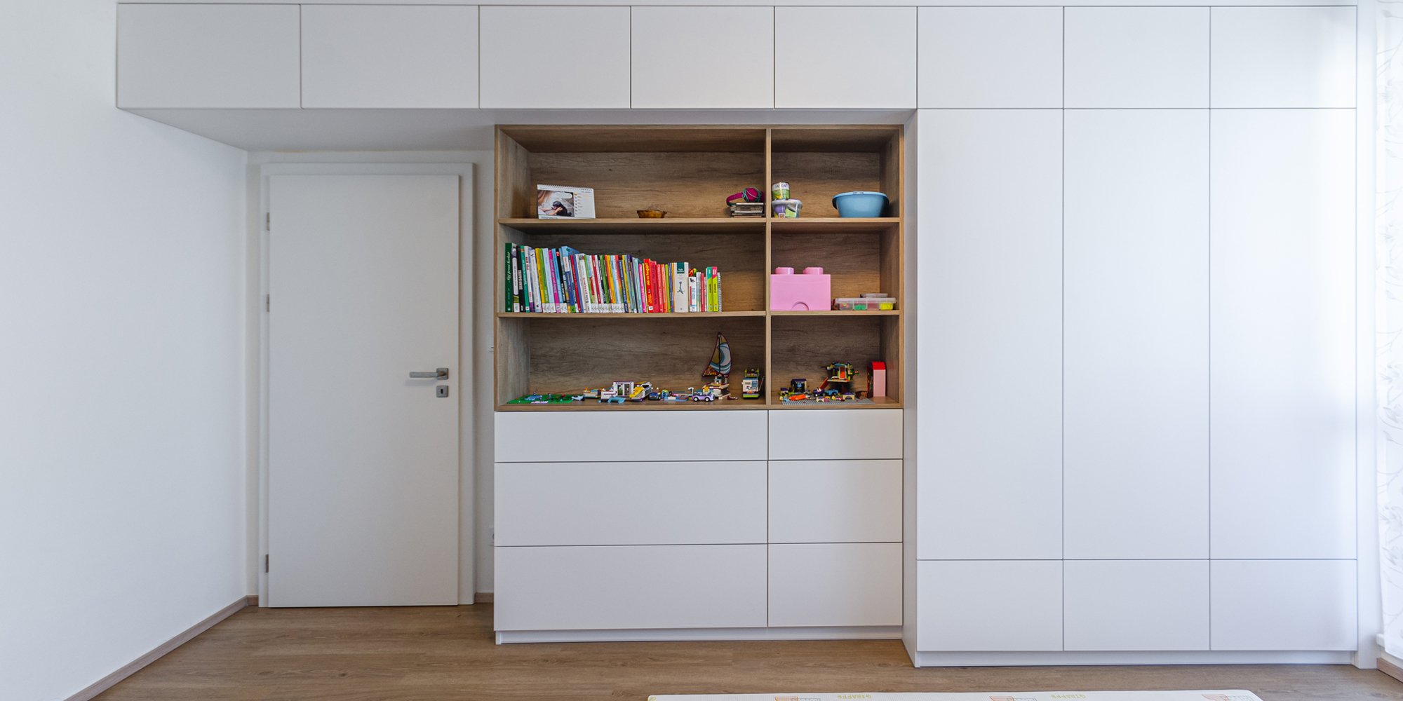 Wooden shelving unit built into the wall amongst hidden storage that gives the wardrobe a minimalistic look