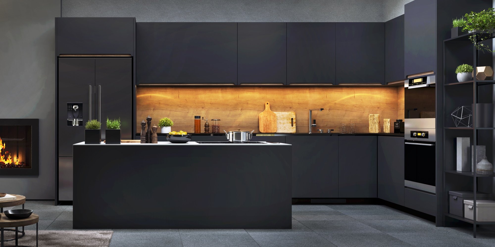 Very dark coloured kitchen with smoothly designed cabinets and appliances, warmed by orange lighting
