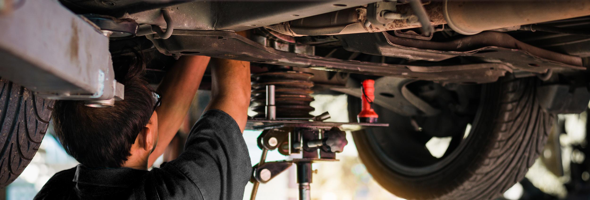 Motor Works Group team member under an elevated vehicle, performing a vehicle service