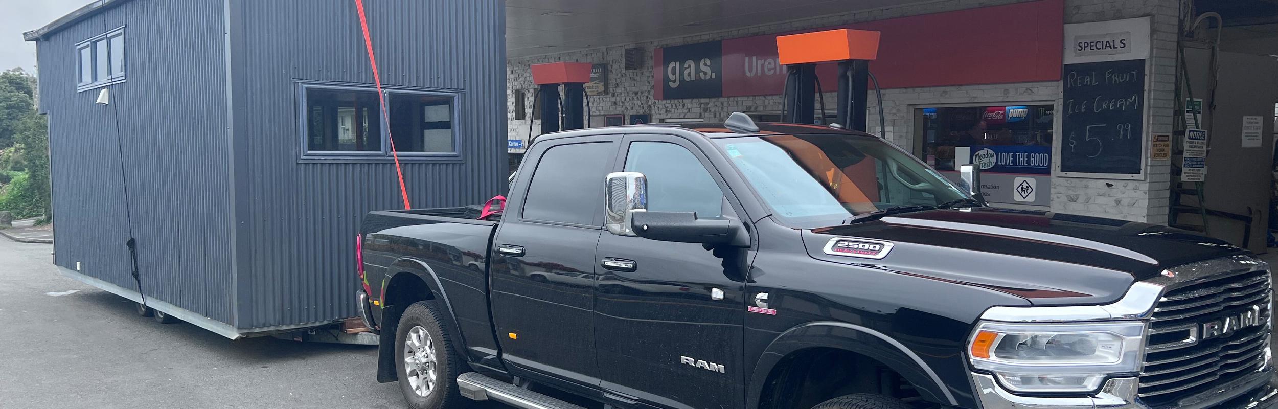 NZ Tiny Home Movers towing a tiny home with a Ram truck, taking a pit stop at the gas station for a fill up