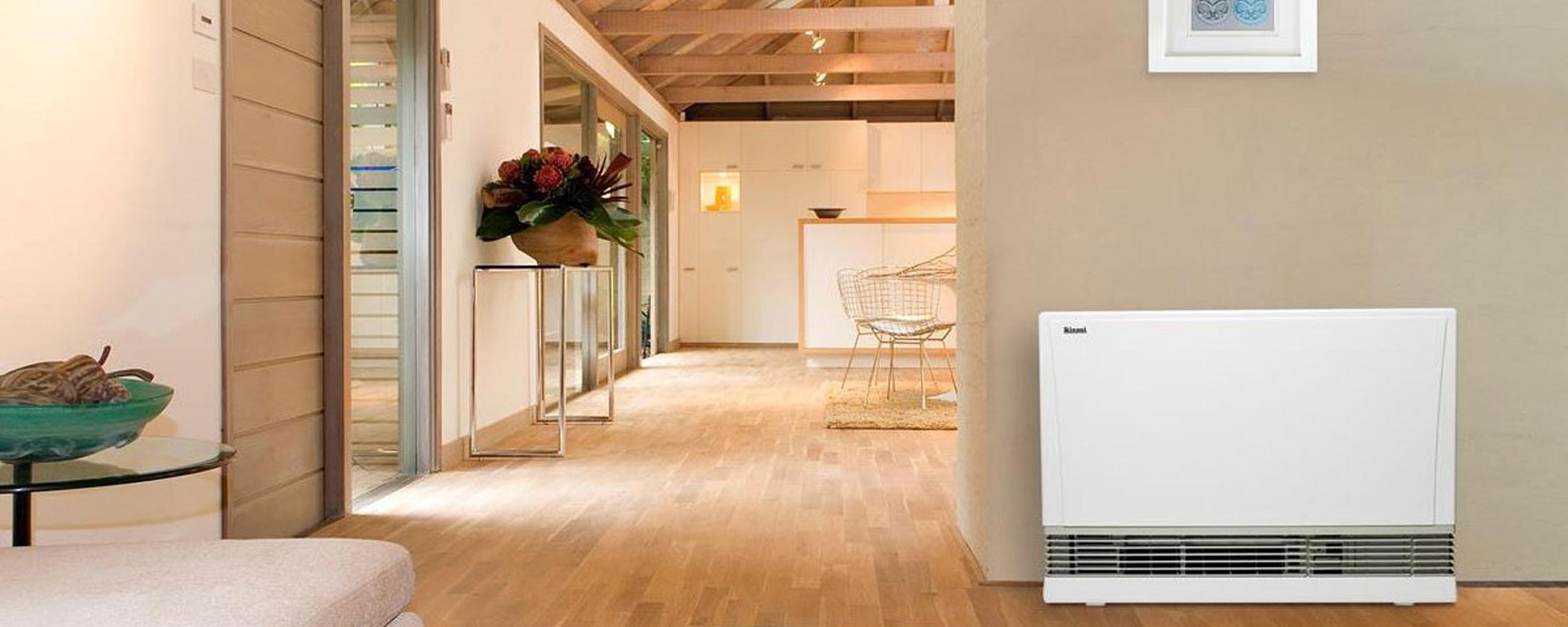 Oak wood floors with a mixture of white and muted earth tone painted walls and a prominent white gas heater against the wall