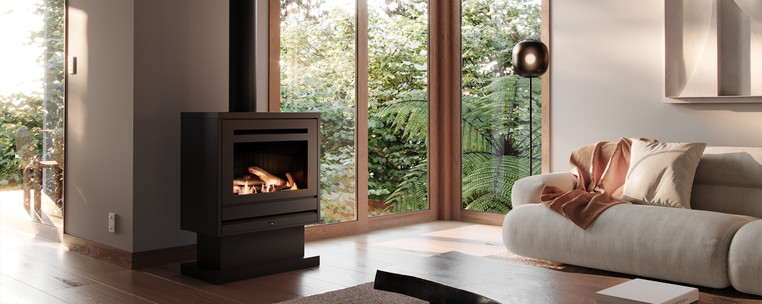 Freestanding wood fire in a living room with earthy tones and floor to ceiling windows that shows off the surrounding nature