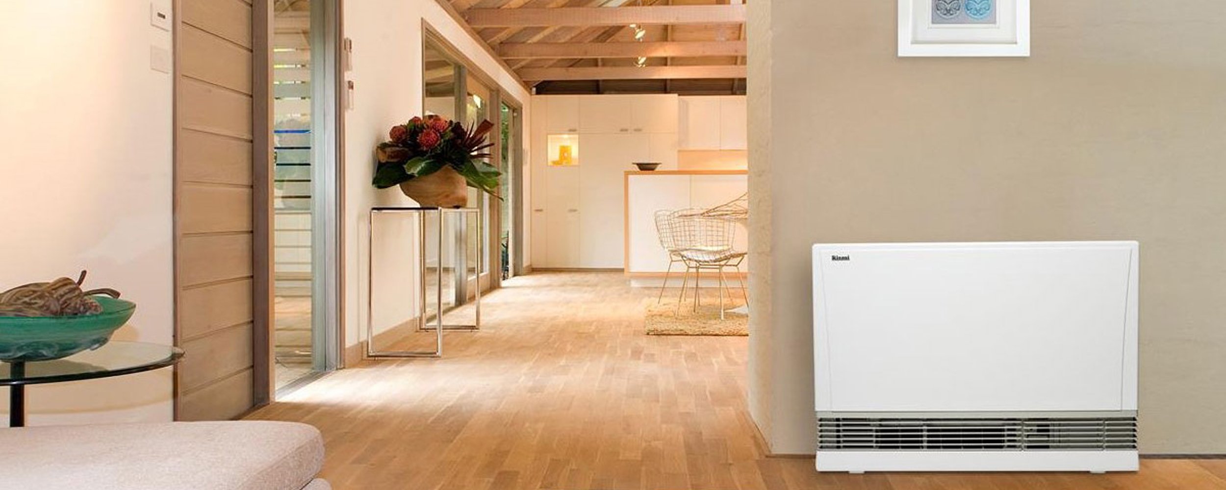Oak wood floors with a mixture of white and muted earth tone painted walls and a prominent white gas heater against the wall