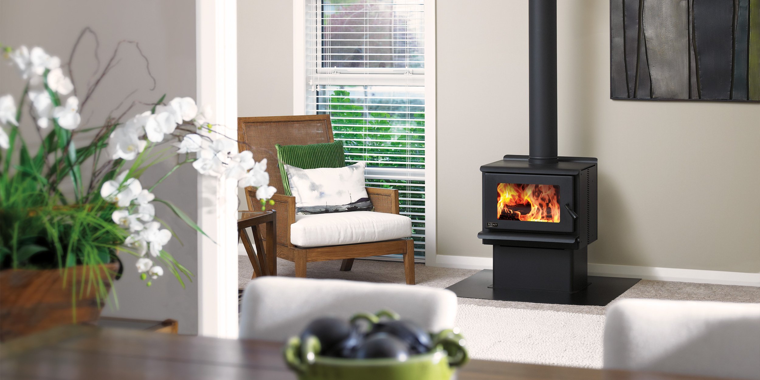 Indoor sitting area with modern furniture and a lit black Kent freestanding wood fire