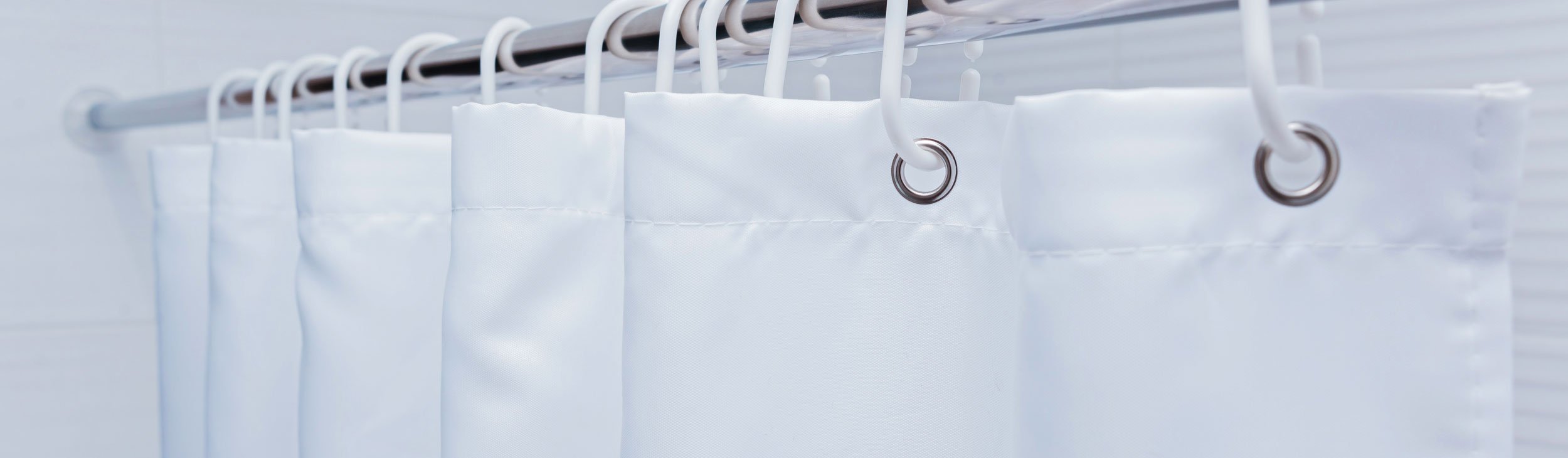 White shower unit interior with a White shower curtain attached to a shiny metal bar with white rings