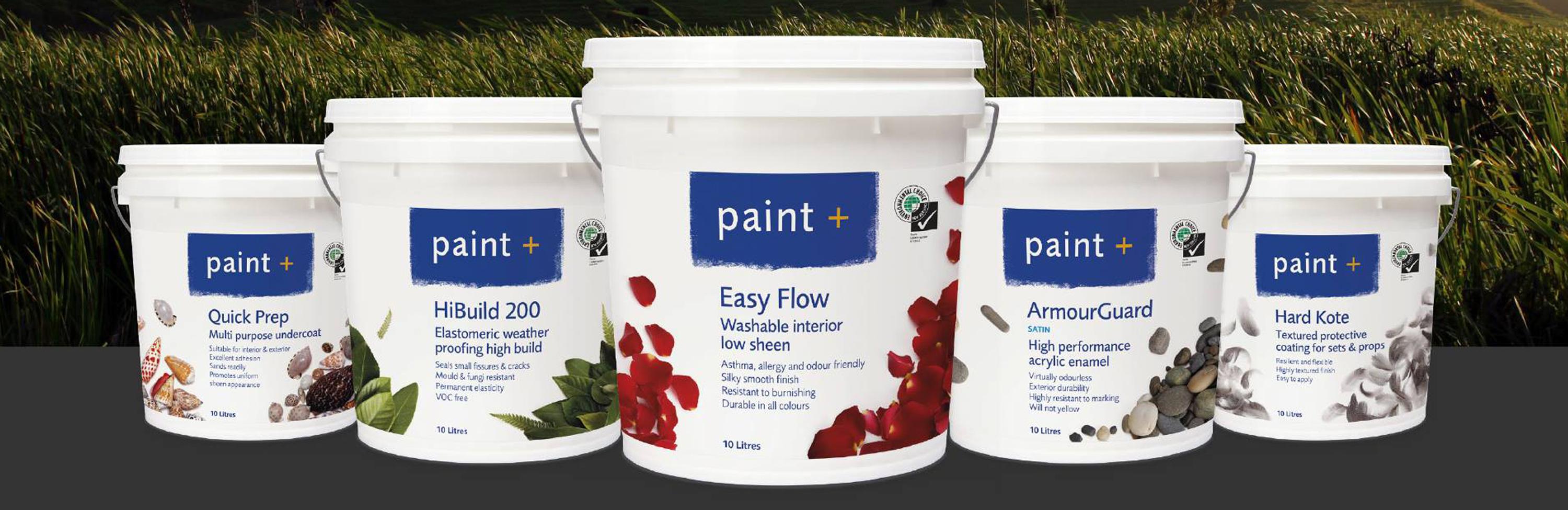 Five different large buckets of paint from paint+ displayed with grass in the background