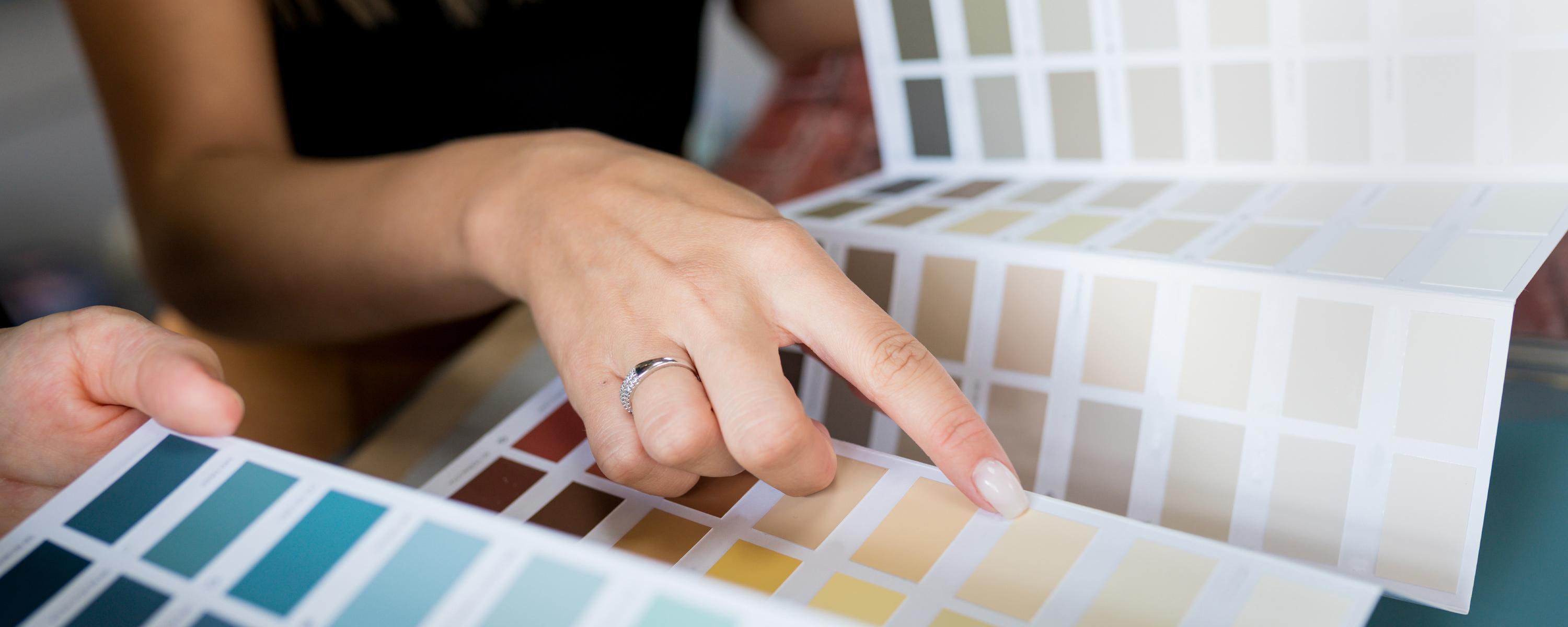 Woman with a wedding ring pointing at a colour in a colour options booklet