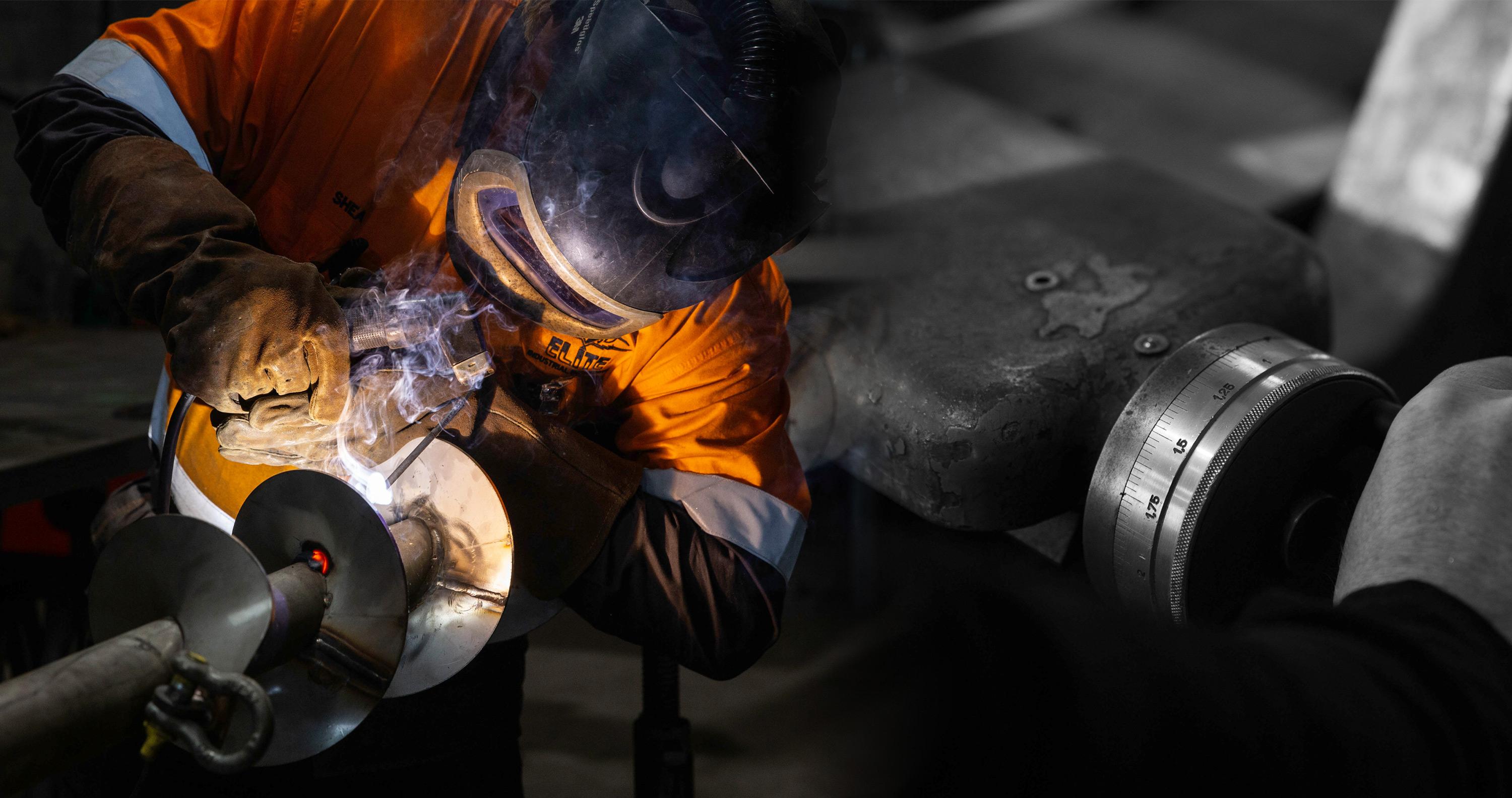 A Man Welding a Excavator Drill Attachment | Engineering Services Feilding