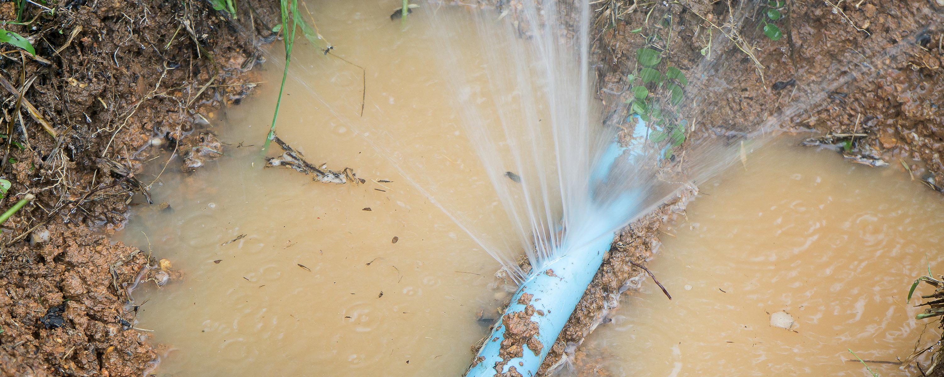 Image of a pipe in ground that has a major leak and is spirting out water | Leak Detection Company Auckland