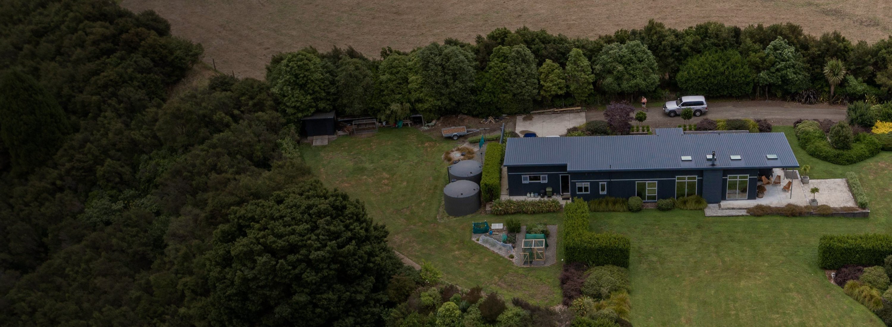 Aerial view of a Rural house on a big block of land with lots of nature and 2 large septic tanks on site.