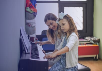 Music teacher and student sitting at an electric keyboard while learning to play