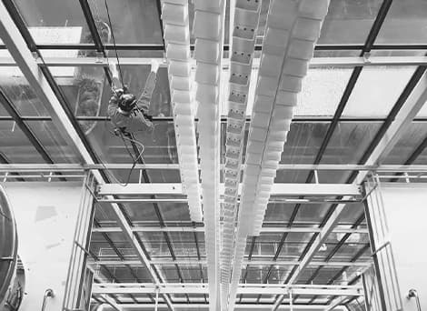 GR Abseiling team member rappelling on the interior wall of a factory with a complete wall of glass windows