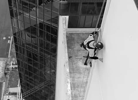 GR Abseiler rappelling down a Waikato commercial building checking for damage and inspecting the building's facade