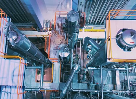 Several massive tall but thin cylinders in a dairy factory with a maze-like walkway and orange guide rails