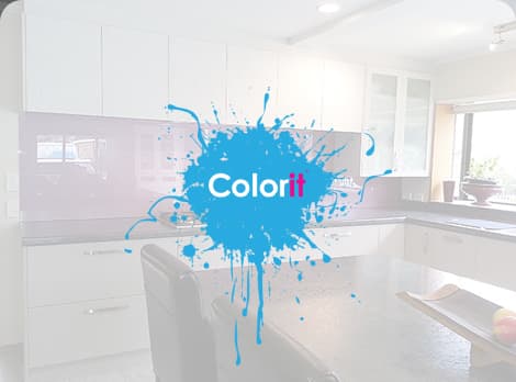 Kitchen with big off-white cabinetry, a dark grey benchtop with a large gas stove and a glossy purple splashback reflecting in the sunlight coming from the window