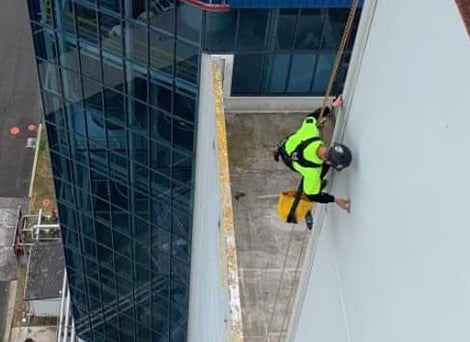 GR Abseiler rappelling down a Waikato commercial building checking for damage and inspecting the building's facade