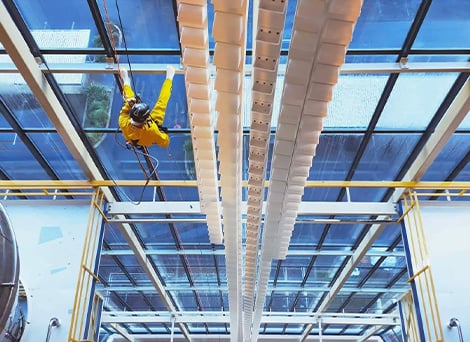 GR Abseiling team member rappelling on the interior wall of a factory with a complete wall of glass windows