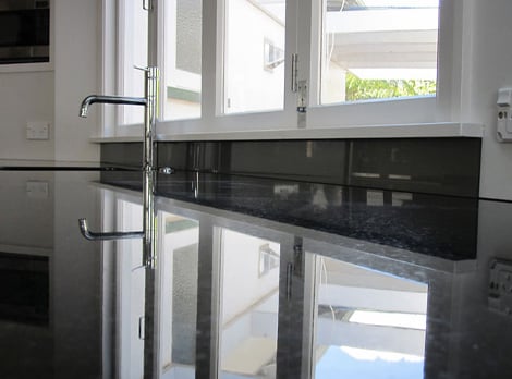 Modern black and white kitchen with a custom made black splashback cut to fit under a window above the sink