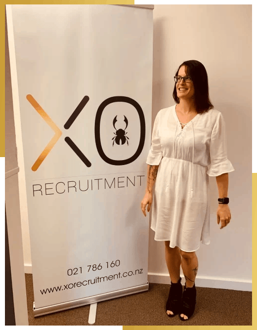 XO Recruitment specialist team member Chloe standing in front of an XO Recruitment banner