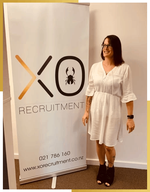 XO Recruitment specialist team member Chloe standing in front of an XO Recruitment banner