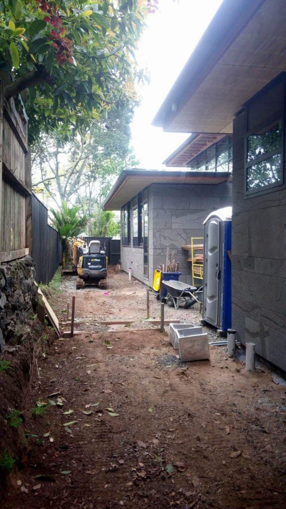 Newly built home with an excavated side lawn being prepared for new soil and grass