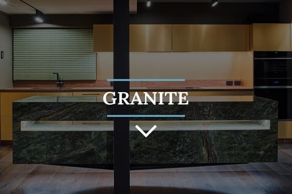 Green and blue nature-like granite island benchtop in a kitchen with goldish-orange wood cabinets and white lighting