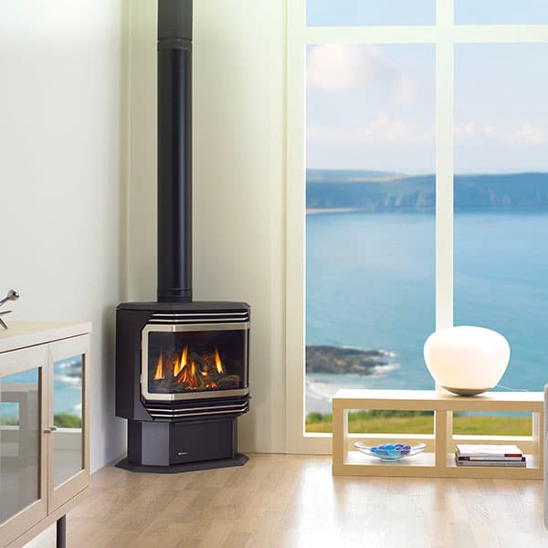 Shiny metallic black freestanding gas fire in the corner of a white living room space with modern furniture