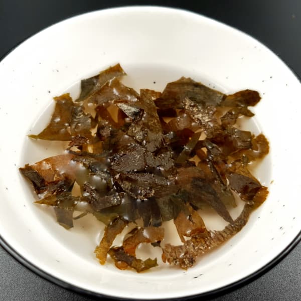 Little white bowl of yellow-green wakame seaweed in water