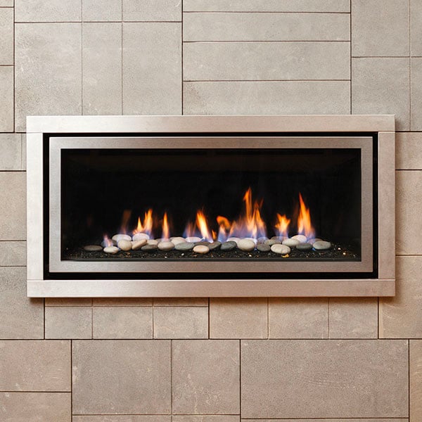 Beige stone tiled wall with an aluminum-framed built-in gas fire that displays stones